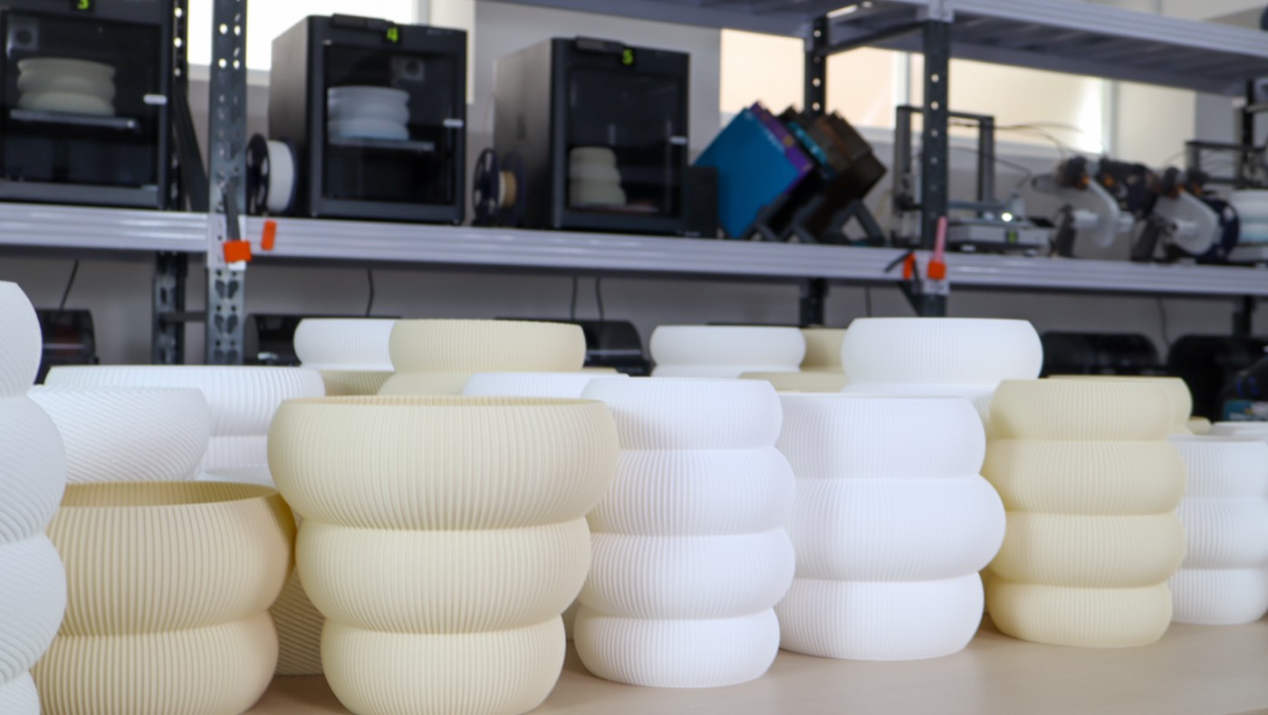 Close-up of ribbed 3D-printed lamp shades — fine vertical print lines across a cluster of warm cream forms